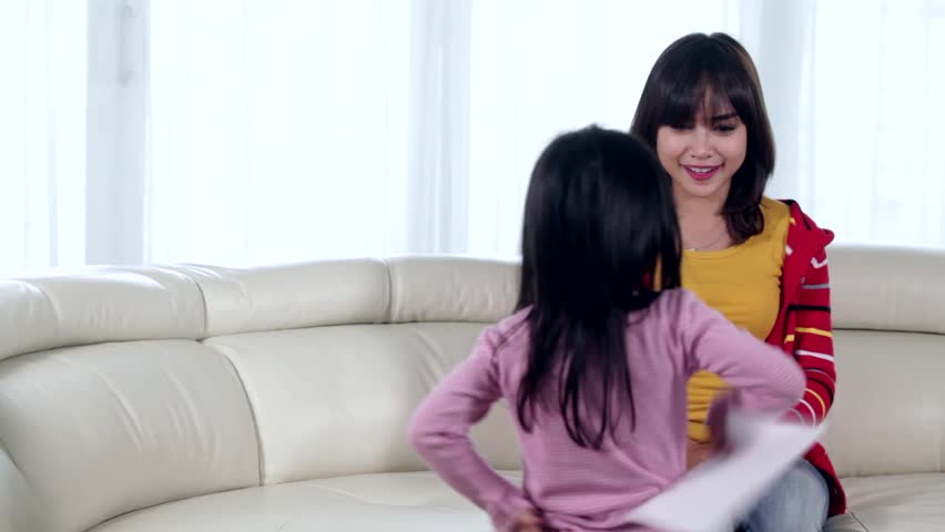 Cute Little Girl Giving A Love Letter On Her Mother While Sitting On The Couch