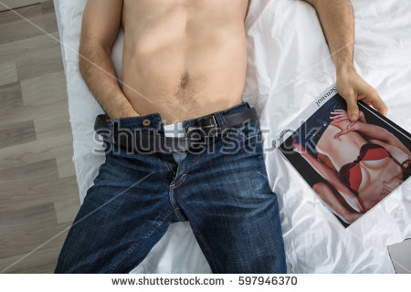 Stock Photo High Angle View Of A Person Masturbating On Bed While Looking At A Sexy Magazine